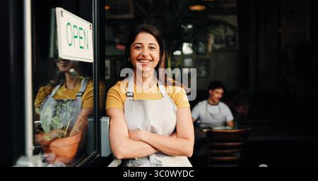 Glückliche Frau, Porträt oder offen mit Vertrauen in ein Café für Startup oder Willkommen in kleinen Unternehmen. Weibliche Person, Kellner oder Besitzer mit einem Lächeln oder überkreuzten Armen Stockfoto