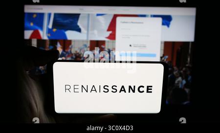 In dieser Abbildung hält eine Person ein Handy mit dem Logo der französischen politischen Partei Renaissance (RE) auf dem Bildschirm vor der Webseite. Stockfoto