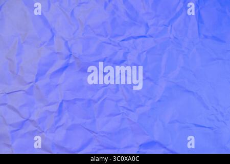 Eine zerknitterte weiße Papieroberfläche, die in sanftes blaues Licht getaucht ist, bietet einen kühlen und beruhigenden Hintergrund für abstrakte Designs oder digitale Vorlagen. Stockfoto
