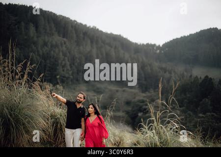 Wunderschönes Paar in Grün. Frau in Rot schaut in die Kamera. Lebendiger Outdoor-Look Stockfoto