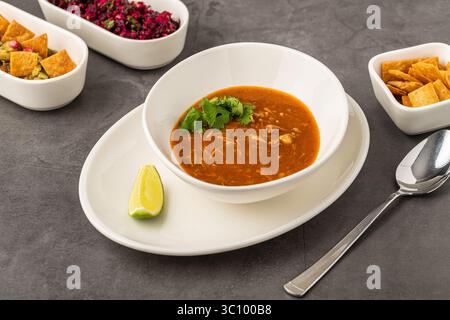 Scharfe mexikanische Hühnersuppe mit Nudeln, garniert mit frischem Koriander und Limettenkeil Stockfoto