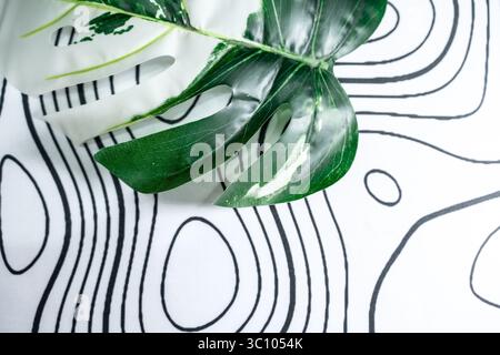 Minimalistisches weißes Textil mit organischen schwarzen Linienmustern und Monstera-Blattdekor. Ideal für Grafikdesign, Layout-Hintergründe oder beruhigende Anwendungen. Stockfoto