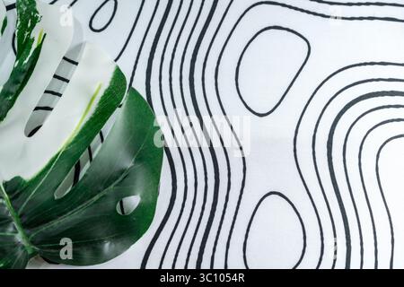 Minimalistisches weißes Textil mit organischen schwarzen Linienmustern und Monstera-Blattdekor. Ideal für Grafikdesign, Layout-Hintergründe oder beruhigende Anwendungen. Stockfoto