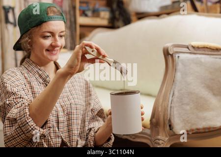 Der Mann ist mit der Malerei und Restaurierung eines alten antiken Sofas beschäftigt, Möbelreparatur Stockfoto