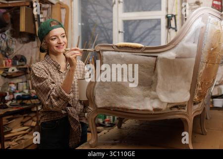 Frau restauriert alten Holzstuhl, Möbelreparatur, Konzept der Reparatur und Restaurierung alter Möbel. Stockfoto