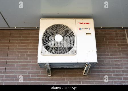 Eine weiße Klimaanlage für den Außenbereich, die zur Kühlung an einer Ziegelwand montiert ist Stockfoto