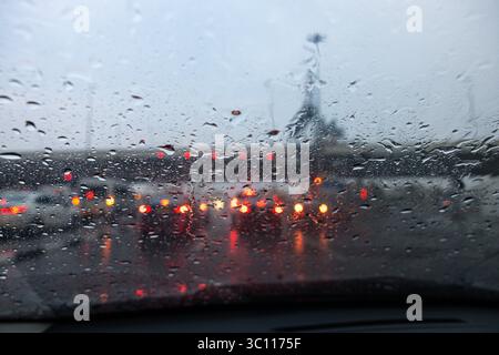 Verkehr an regnerischen Tagen mit Blick auf die Straße durch das Autofenster mit Regentropfen Stockfoto