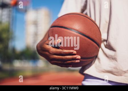 Nahaufnahme einer jungen Frau, die Basketball hält. Sie übt Basketball an sonnigen Tagen. Stockfoto