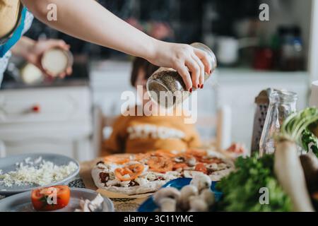 Zubereitung einer hausgemachten Pizza in der Küche mit frischen Zutaten Stockfoto