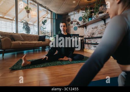 Zwei Personen nahmen an einer Yoga-Sitzung in einem ruhigen Zuhause Teil Stockfoto