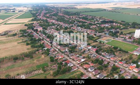 Vorstädtische Wohngegend aus der Vogelperspektive mit freistehenden Häusern, Dächern, Gärten, Straßen und offenem Ackerland. Kleine Balkanstadt, Osteuropa. Stockfoto