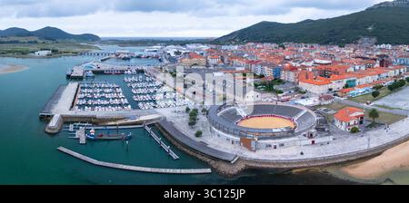 Aus der Vogelperspektive von einer Drohne auf die Stierkampfarena Santoña und den Fischerhafen. Santoña, Victoria und Joyel Marshes Naturpark. Kantabrisches Meer. Kantabrien. Spanien Stockfoto