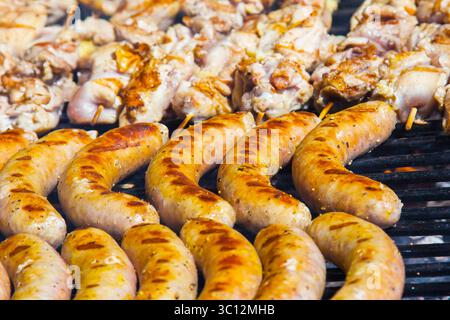 Würstchen und Fleisch auf Holzspießen auf dem Grill, Nahaufnahme. Stockfoto