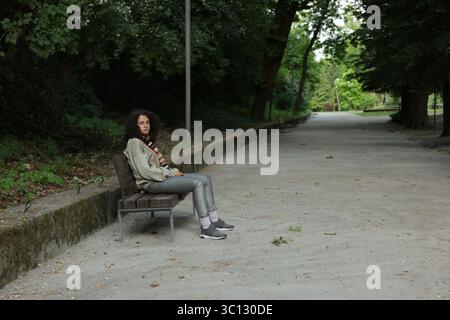 Obdachlose Frau, die auf einer Bank im Park sitzt, Platz für Text Stockfoto