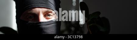 Porträt eines Mannes mit schwarzer Maske, der in die Kamera schaut Stockfoto