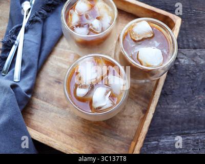 Kalt gebrühter Eiskaffee in hohem Glas auf hölzernem Hintergrund. Schokolade, Vanille, Karamell oder Zimt Eiskaffee in hohem Glas Stockfoto