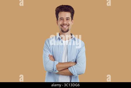 Porträt eines lächelnden jungen Mannes mit sauber rasiertem Bart und Schnurrbart, in weißem T-Shirt und blauem Hemd gekleidet, selbstbewusst gerade aussehend, Arme Stockfoto