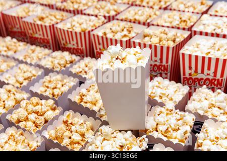 Reihen von gestreiften roten und weißen Popcorn-Boxen gefüllt mit Karamell-Popcorn. Eine Box steht in der Mitte heraus. Stockfoto