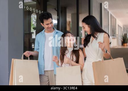 Joyful Family genießt ein Holiday Shopping-Abenteuer mit lächelnden Eltern und Kindern, die Einkaufstaschen tragen Stockfoto