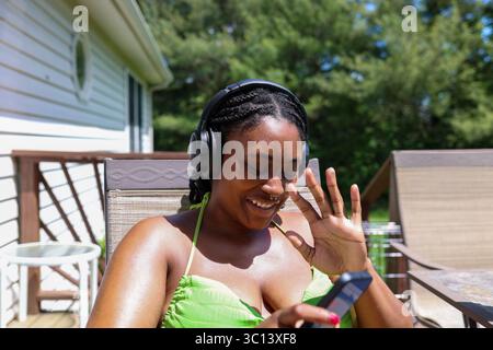 Ein Porträt Einer jungen schwarzen Frau, die Musik mit Kopfhörern hört Stockfoto