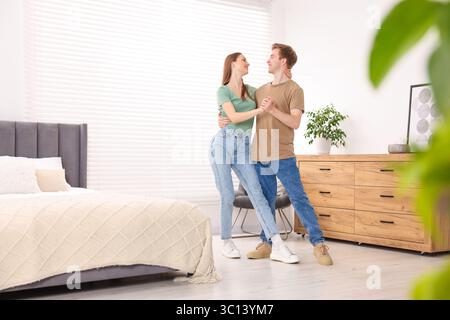 Glückliches junges Paar, das im Schlafzimmer zusammen tanzt Stockfoto