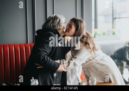 Eine ältere Frau und eine jüngere Frau teilen einen herzlichen Moment in einem gemütlichen Café Stockfoto