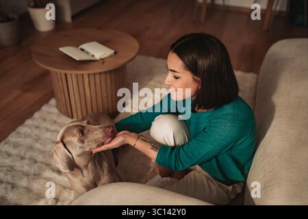 Eine Frau und ihr geliebter Hund genießen einen gemütlichen und intimen Moment zu Hause Stockfoto