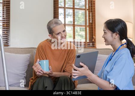 Junge Krankenschwester bietet Gesundheitsberatung für ältere Frauen in einer gemütlichen häuslichen Umgebung, fördert Wellness und unterstützende Pflege für Senioren Stockfoto