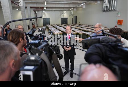 22. Juli 2025, Niedersachsen, Unterlüß: Grant Hendrik Tonne (SPD), niedersächsischer Minister für Wirtschaft, Verkehr und Bau, steht vor Artilleriegeschossen im Kaliber 155 mm und beantwortet Fragen von Medienvertretern nach einem Rundgang durch die neue Munitionsfabrik der Rüstungsfirma Rheinmetall. Der Besuch des Rüstungsunternehmens ist Teil der Sommerreise des niedersächsischen Wirtschaftsministers. Foto: Marcus Brandt/dpa Stockfoto