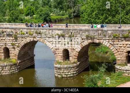 Menschen auf der aus römischen Steinen gebauten Brücke über den Fluss Guadiana in der spanischen Stadt Merida, früher die römische Stadt Emérita Augusta Stockfoto