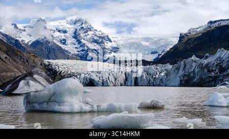 Der Svinafellsjokull-Gletscher erstreckt sich herrlich über die isländische Landschaft, mit riesigen Eisformationen, die auf ruhiges Gletscherwasser treffen. Stockfoto