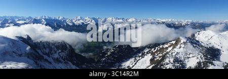 Panoramablick auf die wunderschönen Berge vom Stockhorn Peak mit schneebedeckten Berggipfeln, blauem Himmel und mystischen Talwolken, Schweiz Stockfoto