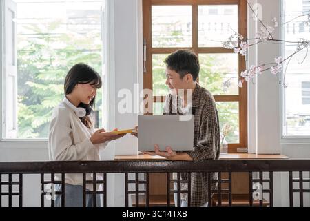 Vielfältige Gruppe von Studenten, die in einer gemütlichen Lernumgebung mit Laptops und Büchern an Hausaufgaben arbeiten Stockfoto