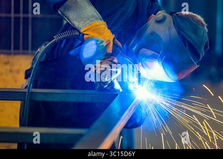 Deutschland - Themenfoto: Metallindustrie. Ein industrieller Schweißer schweißt ein Werkstück. Stockfoto