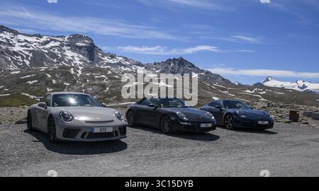 Drei Porsche 911 Sportwagen parkten auf einer Alpenstraße oberhalb der Baumgrenze, links 911 991 GT3, in der Mitte 911 997 Carrera 4, 911 992 Carrera Stockfoto