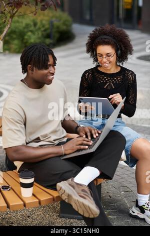 Stilvolles junges afroamerikanisches Paar, das sich mit Fernarbeit beschäftigt und Ideen im Freien ausgetauscht hat. Stockfoto