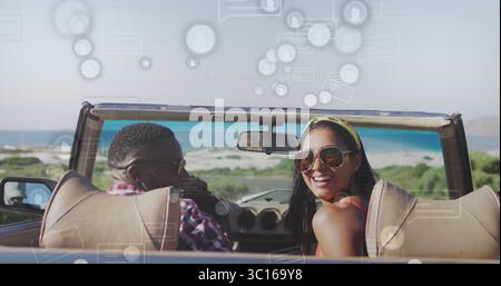 Fahrendes Paar mit Sonnenbrille auf einer Cabriolet-Küstenstraße mit digitaler Überlagerung Stockfoto