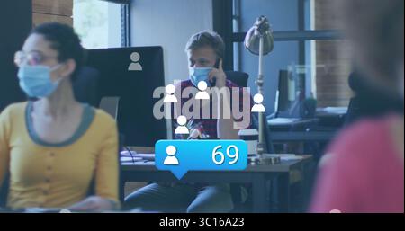 Maskierter Mann mit kariertem Hemd, der im Büro auf dem Handy spricht, mit Monitoranzeige-Overlay Stockfoto