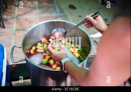 Großer Topf aus Edelstahl mit Sangria und frischem Obst, der im Freien serviert wird, zeigt eine festliche Atmosphäre der Geselligkeit und des Genießens erfrischender h Stockfoto