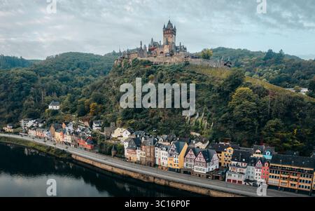 Blick aus der Vogelperspektive auf die Reichsburg Cochem auf einem grünen Hügel mit Blick auf farbenfrohe Gebäude am Ufer, Cochem, Rheinland-Pfalz, Deutschland. Stockfoto
