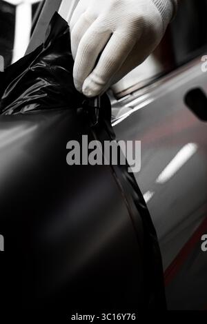 Die Anwendung „Auto Wrap“ ändert das Erscheinungsbild des Fahrzeugs. Vinyl-Verpackung Für Autos Mit Vollpaneel. Die großformatige Vinylfolie verwandelt das Außendesign des Fahrzeugs Stockfoto