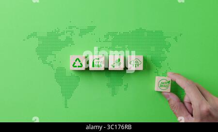 Nettonemissionsfreies und kohlenstoffneutrales 2050-Konzept. Hand platziert Holzwürfelblock mit Netz-Null-Symbolen auf grünem Hintergrund der Weltkarte. CO2 reduzieren Stockfoto