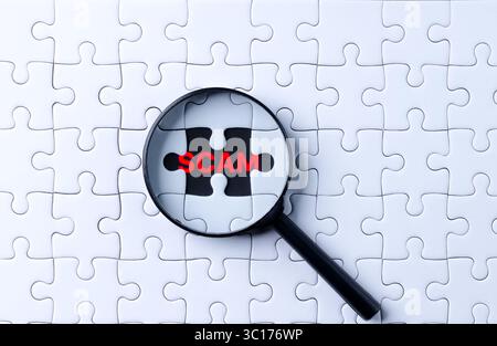 Das Konzept der Technologie zur Bekämpfung von Betrug und Betrug. Hand hält eine Lupe und fokussiert sich auf das Betrugswort auf einem Puzzle. Internetbetrug, Online Stockfoto