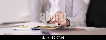 Erwachsene Hand schreibt Geschäftsnotizen in professionelles Notizbuch. Strategische Planung und Konzentration auf Aufgaben. Ideal für Produktivität und Erfolg. Stockfoto