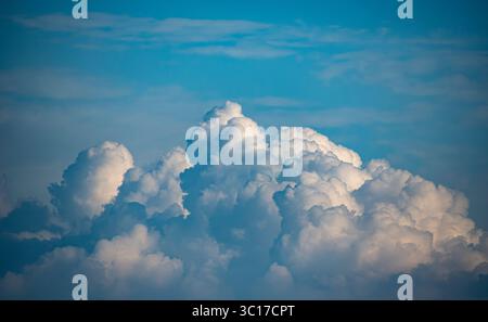 Flauschige weiße Cumulus-Wolken ziehen über einen hellblauen Himmel und schaffen eine beruhigende Atmosphäre. Dieser atemberaubende Blick fängt die Ruhe eines sonnigen Nachmittags ein, perfekt zum Entspannen. Stockfoto