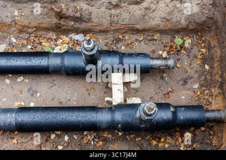 Neue moderne, isolierte städtische Rohrleitungsbaustelle freiliegende unterirdische Rohre in Unterwassergräben. Isolierte Stahlrohre liegen an Stockfoto