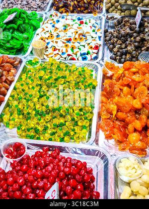 Eine lebendige Marktpräsentation mit kandierten Früchten, Gummigummis und Kaubonbons in verschiedenen Formen, Farben und Texturen, angeordnet in Metalltabletts Stockfoto