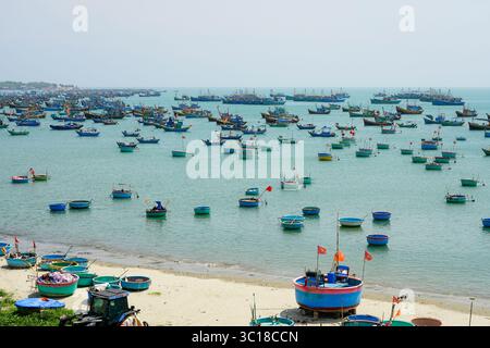 Ein atemberaubender Blick auf traditionelle Rundkorbboote und Fischereischiffe, die friedlich in der Mui ne Bay, Vietnam, ankern Stockfoto