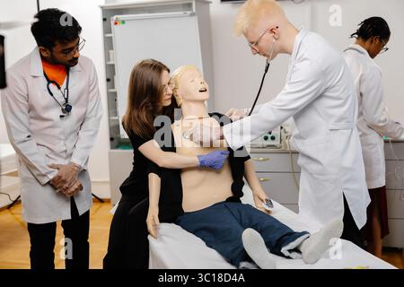 Gruppe verschiedener Medizinstudierenden, die sich mit dem Stethoskop anatomisches Modell während der Praxissitzung untersuchen Stockfoto