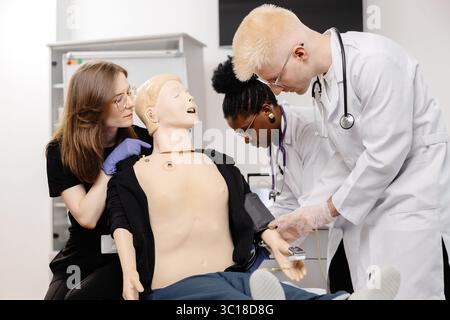 Gruppe verschiedener Medizinstudierenden, die sich mit dem Stethoskop anatomisches Modell während der Praxissitzung untersuchen Stockfoto